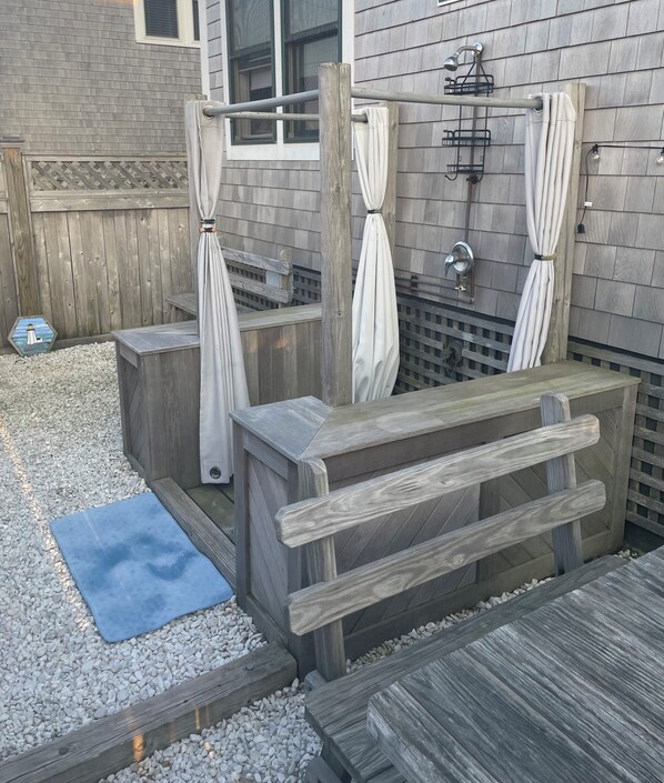 Une terrasse en bois avec un tapis bleu, un banc en bois et une petite table.