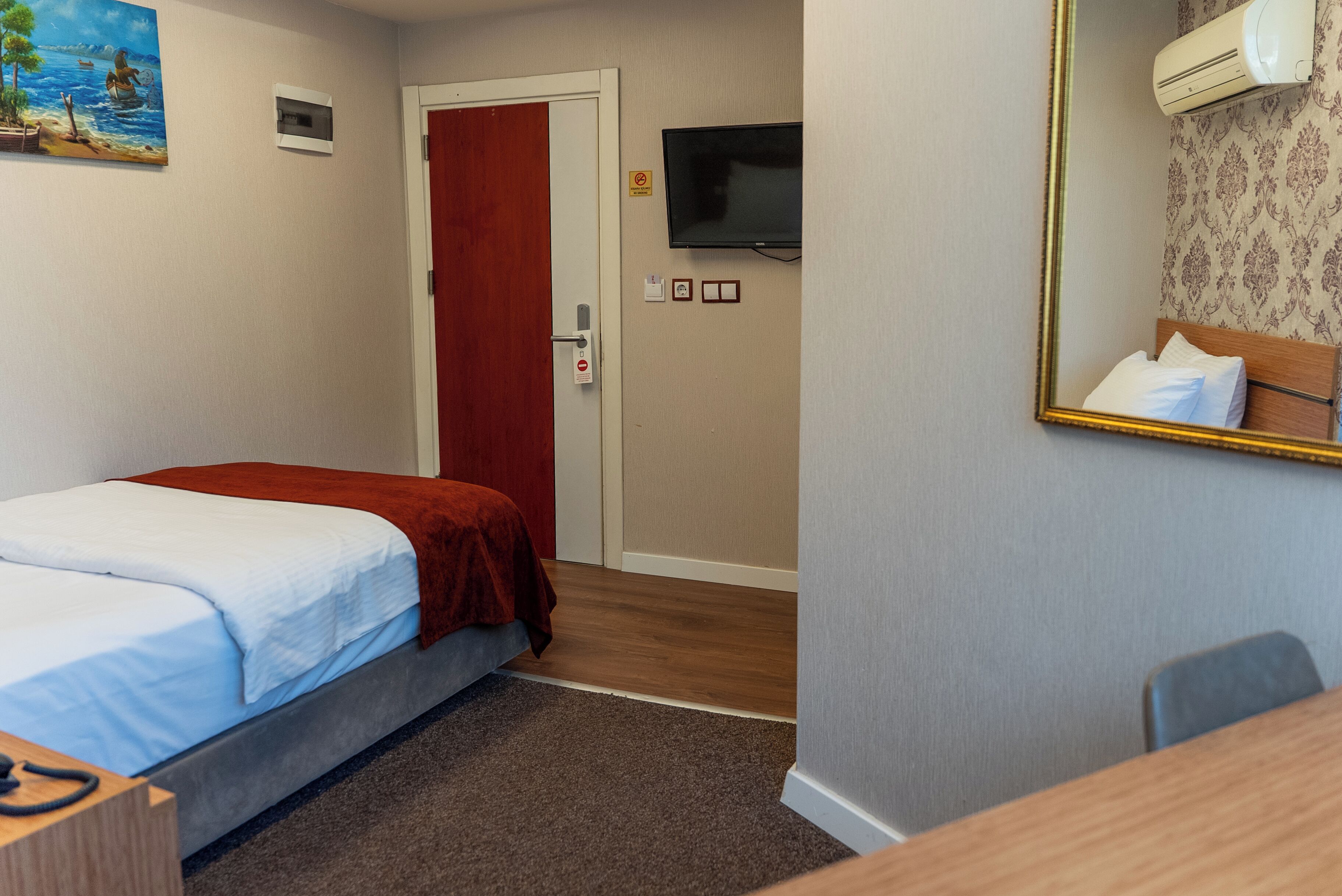 Una habitación de hotel con cama, escritorio, televisión y puerta.