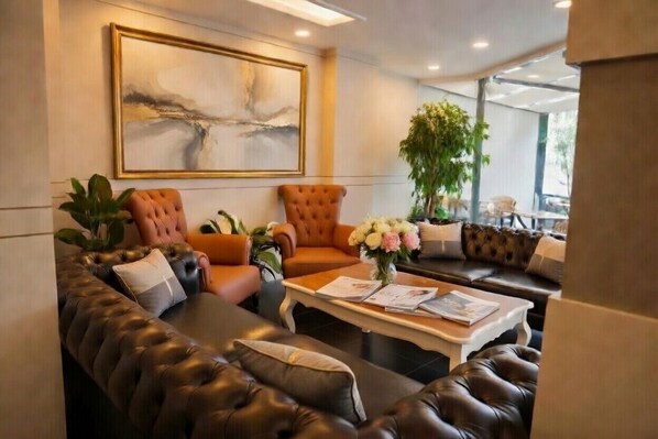 Un espace de détente moderne avec des canapés en cuir, une table basse et un grand tableau abstrait accroché au mur.