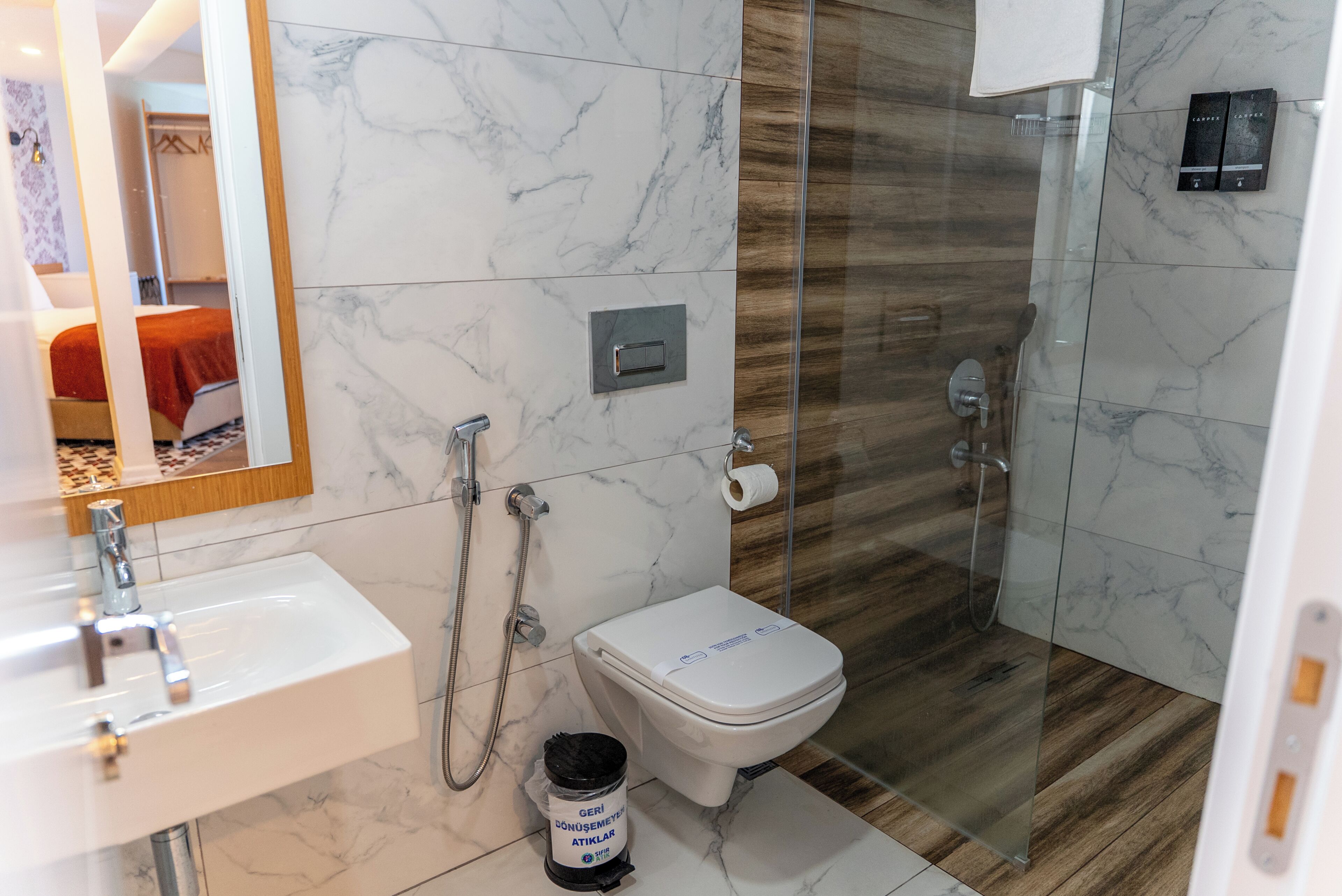 Un baño moderno con lavabo de mármol, inodoro y cabina de ducha de vidrio.