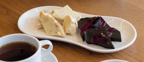 A wooden table with two white cups of tea and a white plate with food.