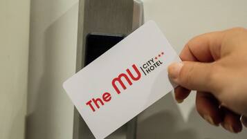 Una mano sostiene una tarjeta con la inscripción 'The MU City Hotel'.