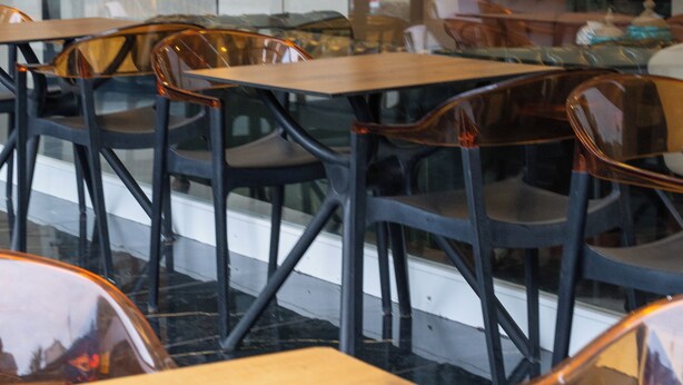 A restaurant interior with wooden tables and chairs, a glass partition, and a view of the outside. - THE MU CITY HOTEL (Trabzon)