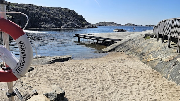 A rocky shoreline with a lifebuoy, a pier, and a wooden structure.