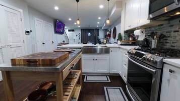 A modern kitchen with white cabinets, stainless steel appliances, and a wooden island.