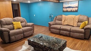 A living room with two brown sofas, a glass coffee table, and a blue wall with a painting. - Charming 2-bedroom apartment with WiFi, AC in fabulous Rapid City (Rapid City)