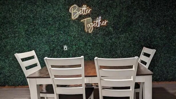 A dining table with four white chairs and a neon sign that reads "Better Together" against a green wall. - Charming 2-bedroom apartment with WiFi, AC in fabulous Rapid City (Rapid City)