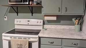 A kitchen with a white stove, a microwave on a shelf, and light green cabinets. - Charming 2-bedroom apartment with WiFi, AC in fabulous Rapid City (Rapid City)