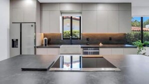 A modern kitchen with a central island, built-in appliances, and a large window. - Modern 4 bedroom stay Oasis Villa with Turkish bath (Coral Gables)