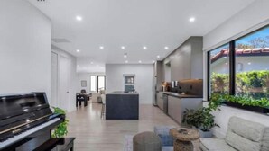 A modern living room with a piano, a sofa, and a dining area in the background. - Modern 4 bedroom stay Oasis Villa with Turkish bath (Coral Gables)