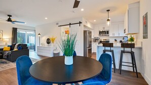 Une cuisine moderne avec des meubles blancs, un îlot central et des tabourets de bar.
