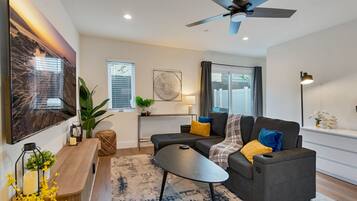 A modern living room with a sofa, coffee table, and a ceiling fan.