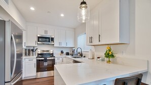 Une cuisine moderne avec des meubles blancs, des appareils en acier inoxydable et un îlot en marbre.