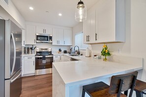 A modern kitchen with white cabinetry, stainless steel appliances, and a marble island. - Lux 3BR w/ King Beds & Fire Pit (La Mesa)