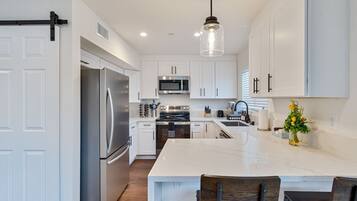 A modern kitchen with white cabinets, stainless steel appliances, and a marble island.