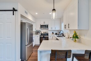 A modern kitchen with white cabinets, stainless steel appliances, and a marble island.