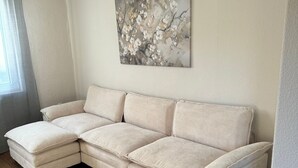 Een beige hoekbank met een gestructureerde stof, geplaatst in een kamer met houten vloeren en een lichtgekleurde muur.