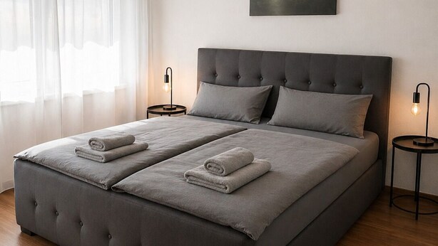 Een moderne slaapkamer met een groot bed, twee nachtkastjes en een schilderij aan de muur.