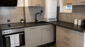 Een moderne keuken met een inbouwoven, een afzuigkap en een boiler.