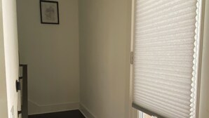 A staircase leading to a door with a window, a framed picture on the wall, and a wooden fence outside.