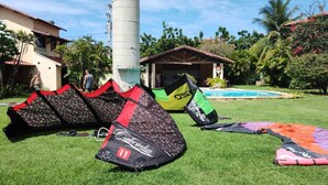 A grassy area with multiple kites and a pool in the background.