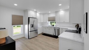 A modern kitchen with white cabinetry, stainless steel appliances, and a large window. - Charming-relaxing 3BR farmhouse *15min from town (Oblong)