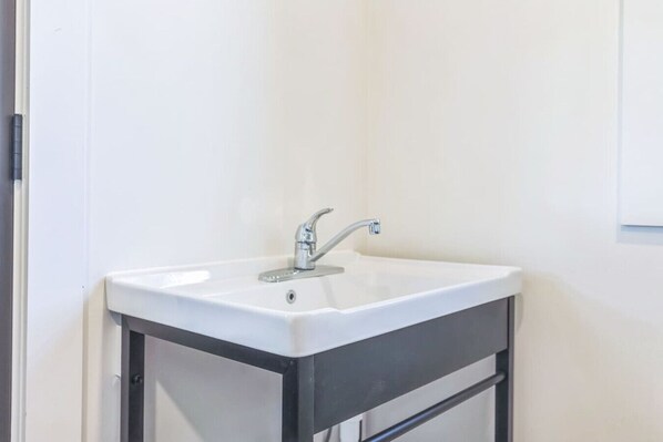 A white bathroom sink with a modern faucet, mounted on a black cabinet. - Charming-relaxing 3BR farmhouse *15min from town (Oblong)