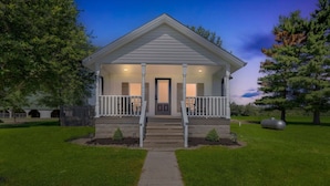 A single-story house with a front porch, a central door, and a small front yard. - Charming-relaxing 3BR farmhouse *15min from town (Oblong)
