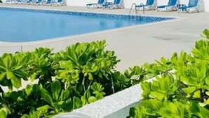 Un espace piscine avec des chaises longues et vue sur l’océan.