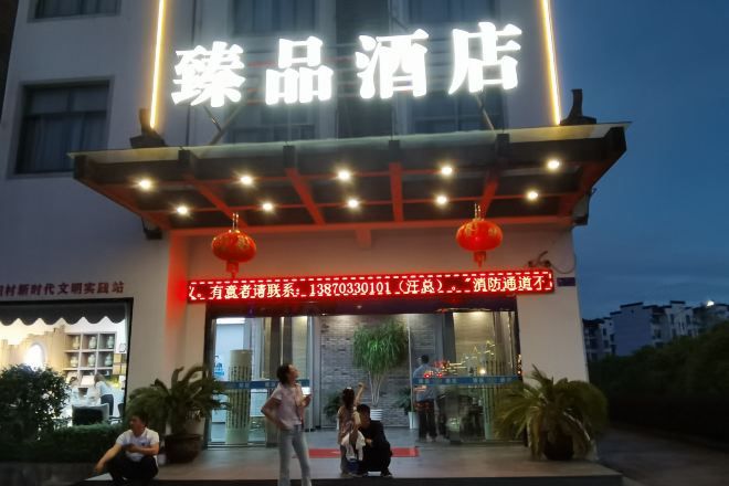 A hotel entrance with a neon sign, a red lantern, and a glass door.