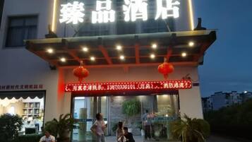 A hotel entrance with a neon sign, a red lantern, and a glass door.