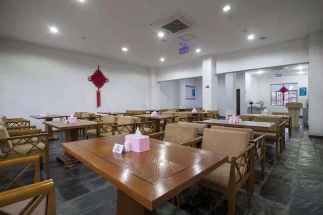 A conference room with tables and chairs, a red decorative element on the wall, and a door in the background.