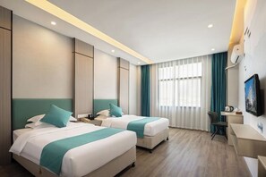 A hotel room with two beds, a desk, a chair, and a television. - Zhenpin Hotel (Wuyuan)