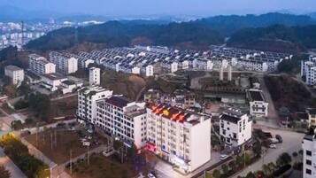A multi-story hotel with a central courtyard, surrounded by residential buildings, and a bridge in the background.