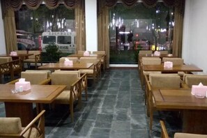 A restaurant with tables and chairs arranged for dining. - Zhenpin Hotel (Wuyuan)
