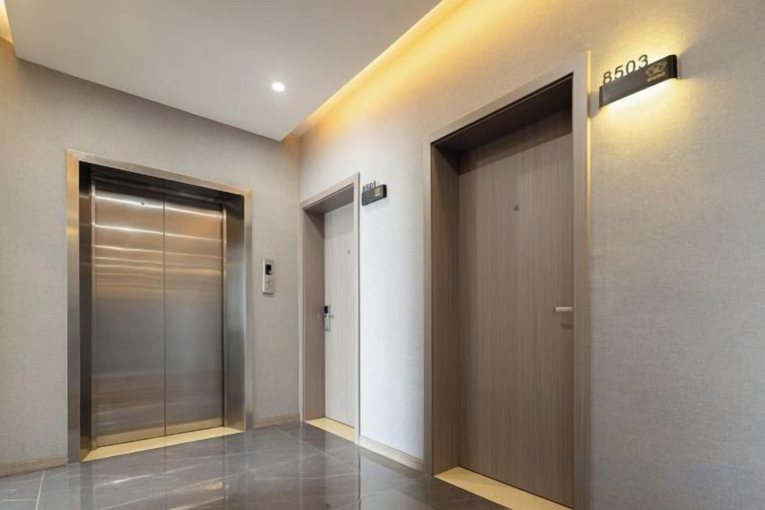 A hallway with two elevators, one metallic and one wooden, and a wall-mounted sign indicating the elevator number.