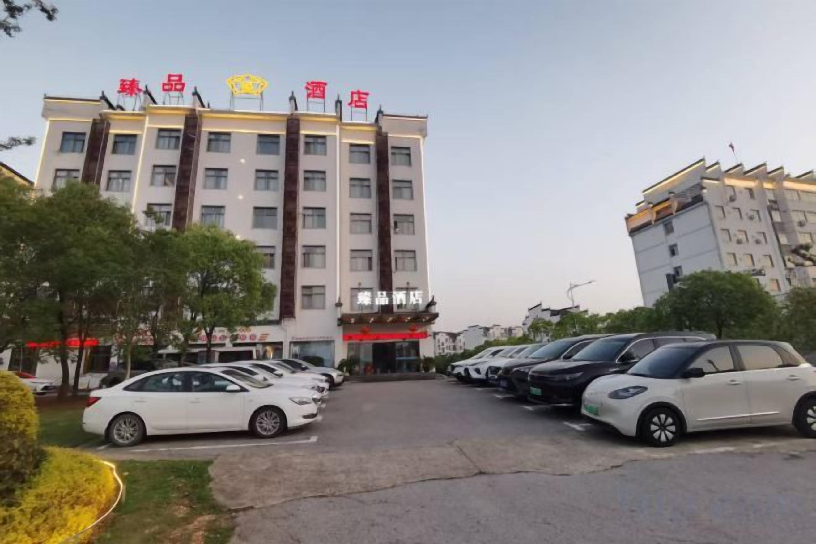Een hotel met meerdere verdiepingen, een parkeerplaats met verschillende auto's en een heldere lucht.