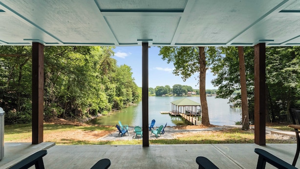 A covered outdoor seating area with a view of a lake and dock.