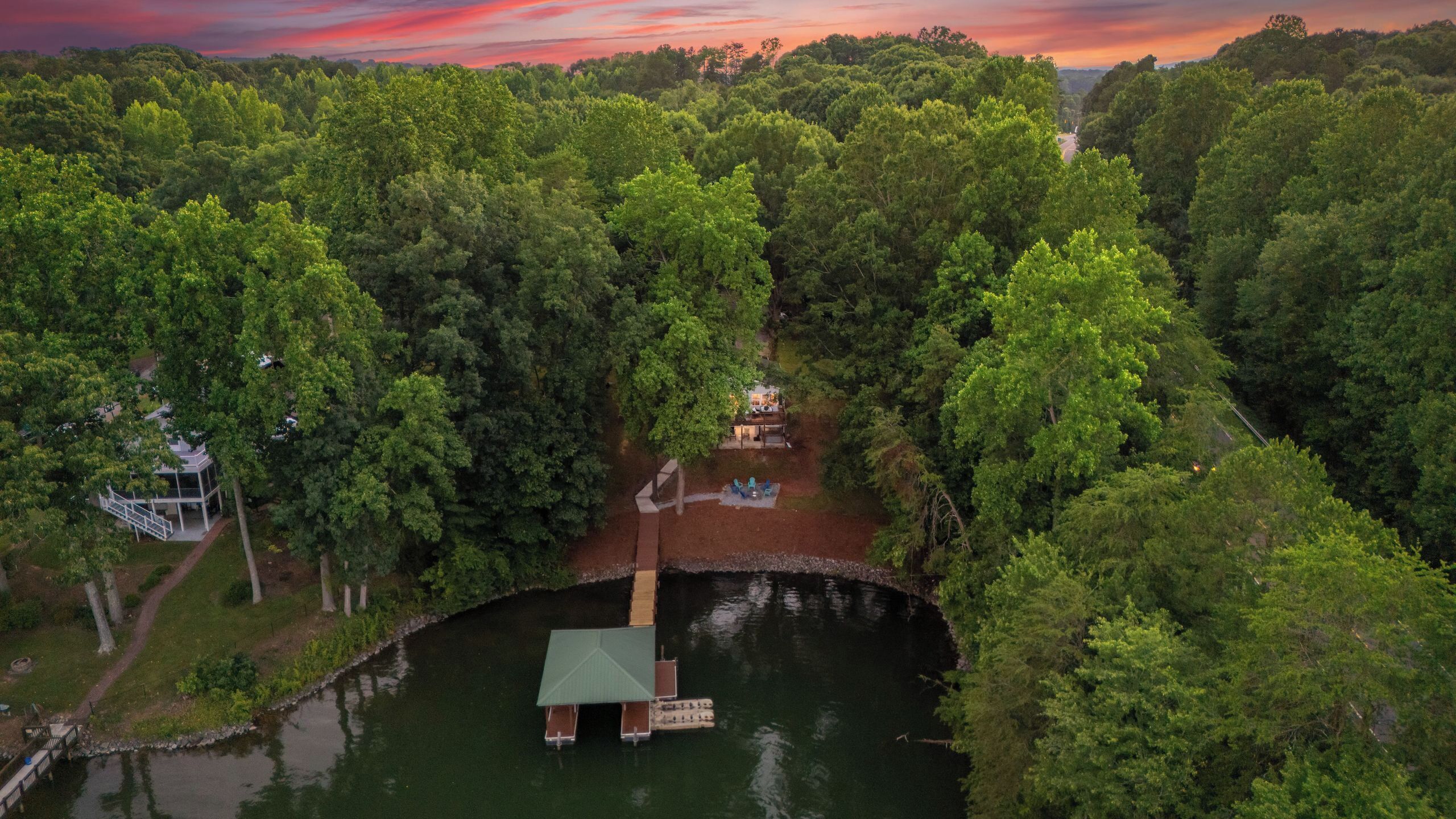 A riverside cabin with a dock, surrounded by dense forest.