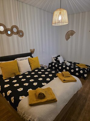 Un dormitorio con dos camas, un lámpara colgante y decoración en la pared.
