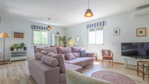 Een woonkamer met een hoekbank, een televisie en een vloerlamp.