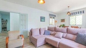 Een woonkamer met een bank, fauteuil en een eethoek met een tafel en stoelen.