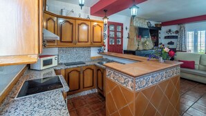 Une cuisine avec des meubles en bois, un four à micro-ondes, une cuisinière et un dosseret carrelé.