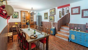Un coin repas avec une table et des chaises en bois, un lustre et un escalier orné de carreaux bleus et blancs.