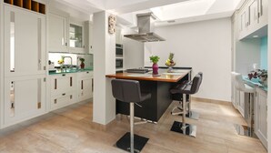 Una cocina moderna con una isla central, un comedor con sillas y vistas del cielo a través del techo.