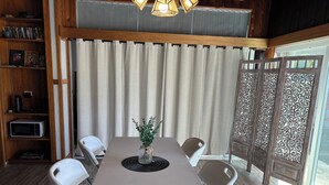 A dining area with a table, chairs, a vase with greenery, a bookshelf, and a decorative partition. - Charming 2-bedroom house in wonderful Pāhoa with free private covered parking (Pāhoa)