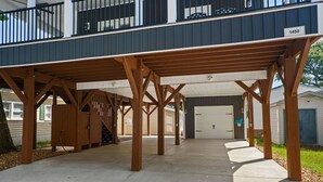 A covered parking area with a wooden structure, a garage door, and a house number 1450.