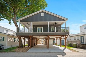 A two-story house with a balcony, a garage, and a tree in the background.