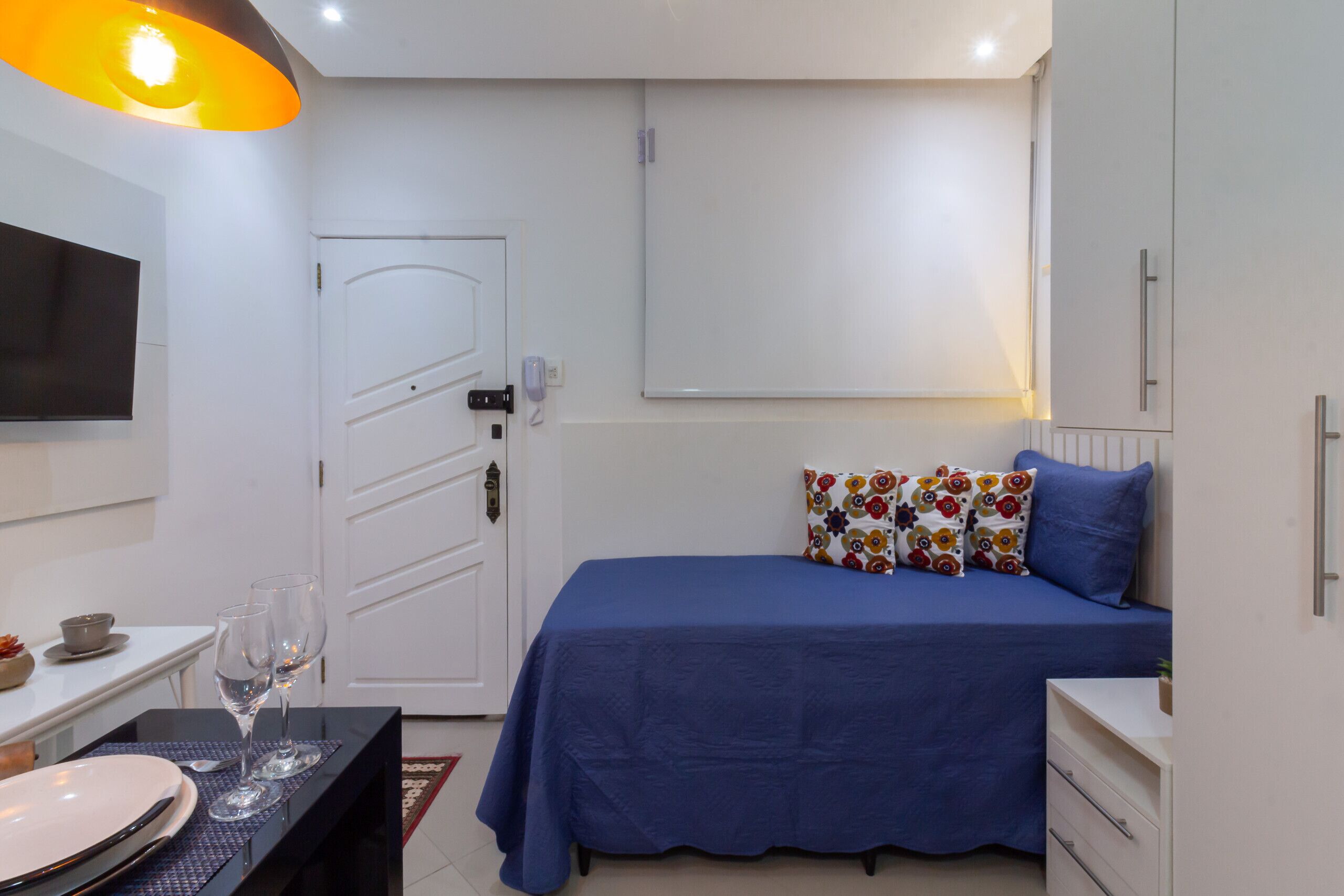 Ein Schlafzimmer mit einem Bett, einem Nachttisch und einem an der Wand befestigten Fernseher.