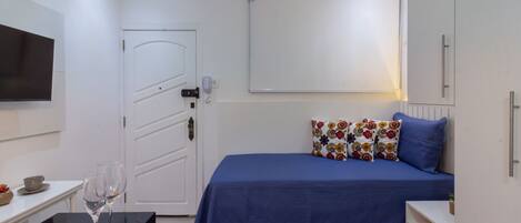 Ein Schlafzimmer mit einem Bett, einem Nachttisch und einem an der Wand befestigten Fernseher.
